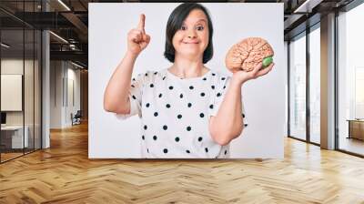 Brunette woman with down syndrome holding brain smiling with an idea or question pointing finger with happy face, number one Wall mural