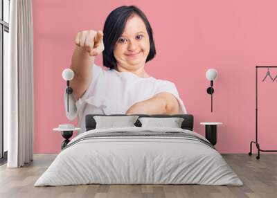 Brunette woman with down syndrome wearing casual white tshirt pointing to you and the camera with fingers, smiling positive and cheerful Wall mural