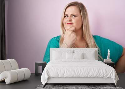 Caucasian plus size woman standing over pink background looking confident at the camera smiling with crossed arms and hand raised on chin. thinking positive. Wall mural