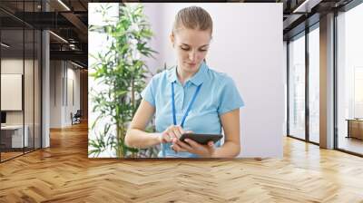 Caucasian woman in blue uniform using tablet at healthcare center Wall mural