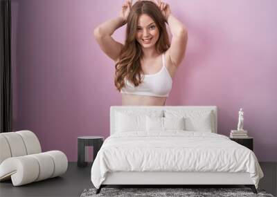 Caucasian woman wearing lingerie over pink background posing funny and crazy with fingers on head as bunny ears, smiling cheerful Wall mural