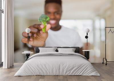 Close up of african american man holding fresh broccoli as healthy food Wall mural