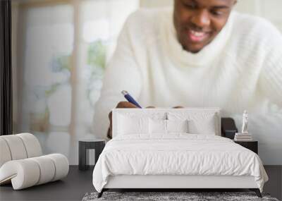 Close up of african man writing a note on a paper smiling confident Wall mural