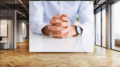 Close up of man with crossed hands over white table Wall mural