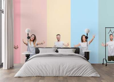 Collage of different ethnics young people wearing white t-shirt over colorful isolated background looking at the camera smiling with open arms for hug. Cheerful expression embracing happiness. Wall mural