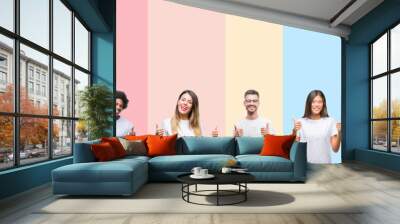 Collage of different ethnics young people wearing white t-shirt over colorful isolated background success sign doing positive gesture with hand, thumbs up smiling and happy. Looking at the camera Wall mural