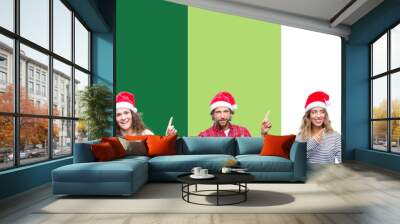 Collage of group of people wearing christmas hat over white and green isolated background smiling and looking at the camera pointing with two hands and fingers to the side. Wall mural