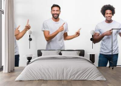 Collage of young caucasian, hispanic, afro men wearing white t-shirt over white isolated background smiling and looking at the camera pointing with two hands and fingers to the side. Wall mural