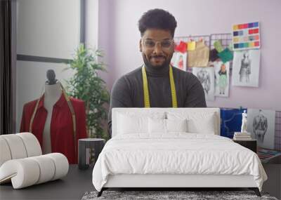 Confident tailor with arms crossed in a design room surrounded by fashion sketches, fabric samples, and a mannequin. Wall mural