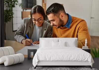 Couple smiling happy reading document at the office. Wall mural