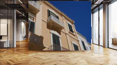 Elegant balconies and shutters adorn a charming two-story building against a clear blue sky in the old town of puglia, italy. Wall mural