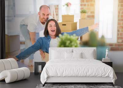 Funny and crazy couple having fun riding a cardboad box as a car, smiling happy and laughing at new home Wall mural