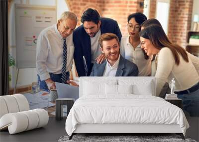 Group of business workers smiling happy and confident. One of them sitting and partners standing around. Working together with smile on face looking at the laptop at the office Wall mural