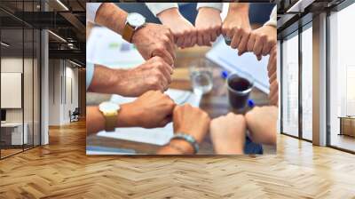 Group of business workers standing bumping fists at the office Wall mural