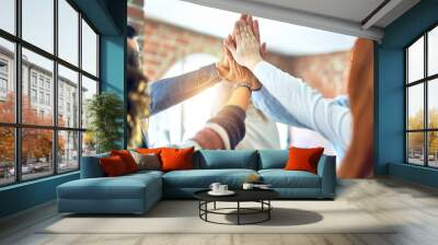 Group of business workers standing with hands together highing five at the office Wall mural