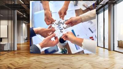 Group of business workers with hands together connecting pieces of puzzle at the office Wall mural