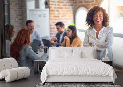 Group of business workers working together. Middle age beautiful businesswoman standing smiling happy looking at the camera at the office Wall mural