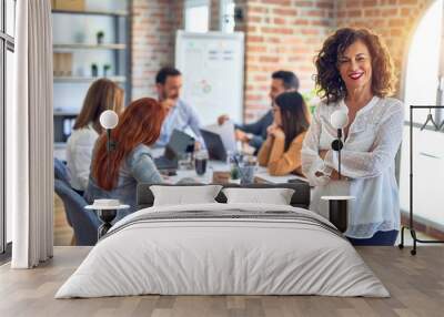 Group of business workers working together. Middle age beautiful businesswoman standing smiling happy looking at the camera at the office Wall mural