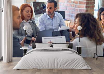 Group of business workers working together. Sitting on desk using laptop reading documents at the office Wall mural