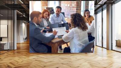 Group of business workers working together. Sitting on desk using laptop reading documents at the office Wall mural