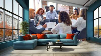 Group of business workers working together. Sitting on desk using laptop reading documents at the office Wall mural