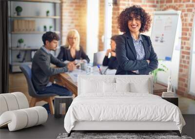 Group of business workers working together. Young beautiful woman standing smiling happy looking at the camera at the office Wall mural