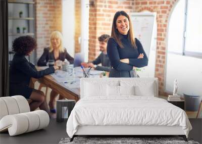 Group of business workers working together. Young beautiful woman standing smiling happy looking at the camera at the office Wall mural