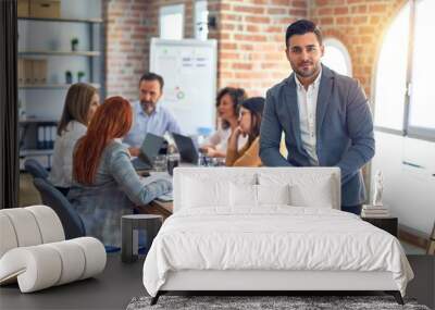 Group of business workers working together. Young handsome businessman standing smiling happy looking at the camera at the office Wall mural