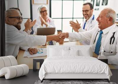 Group of middle age doctor smiling and clapping to partners handshake in a medical meeting at the clinic office. Wall mural