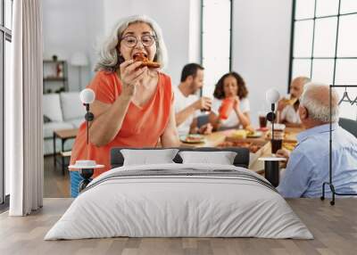 Group of middle age people smiling happy eating italian pizza sitting on the table at home Wall mural