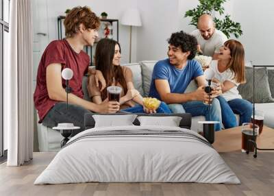 Group of young friends having party sitting on the sofa at home. Wall mural