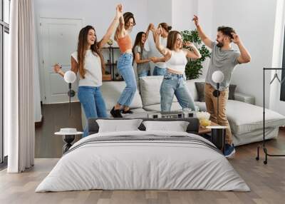 Group of young friends smiling happy and dancing at home. Wall mural