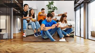 Group of young friends smiling happy playing video game at home. Wall mural