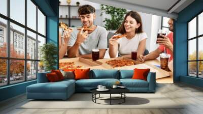 Group of young people smiling happy eating italian pizza sitting on the table at home Wall mural