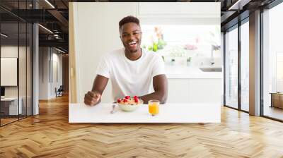 Handsome african american man eating heatlhy cereals and berries as breakfast Wall mural