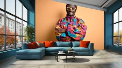 Handsome african american man wearing colorful coat and glasses over yellow background happy face smiling with crossed arms looking at the camera. Positive person. Wall mural