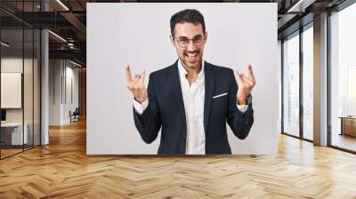 Handsome business hispanic man standing over white background shouting with crazy expression doing rock symbol with hands up. music star. heavy music concept. Wall mural