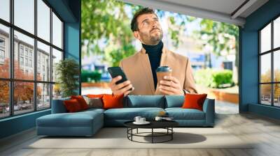 Handsome business man wearing elegant jacket using smartphone outdoors Wall mural