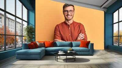 Handsome caucasian man wearing casual clothes and glasses happy face smiling with crossed arms looking at the camera. positive person. Wall mural