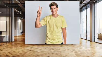 Handsome caucasian man wearing casual clothes showing and pointing up with fingers number two while smiling confident and happy. Wall mural