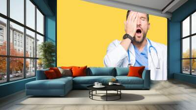 Handsome doctor man wearing medical uniform over isolated background Yawning tired covering half face, eye and mouth with hand. Face hurts in pain. Wall mural