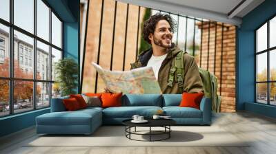 Handsome hispanic man looking at travel map at the city Wall mural