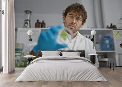 Handsome hispanic man with beard and labcoat in a laboratory holding a test tube. Wall mural