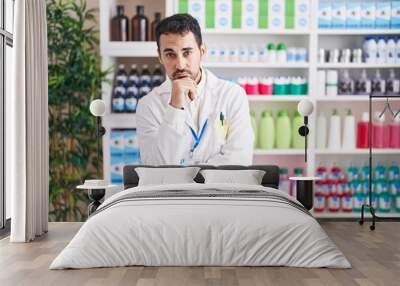 Handsome hispanic man working at pharmacy drugstore thinking looking tired and bored with depression problems with crossed arms. Wall mural