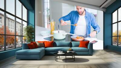 Handsome man cooking pasta at home Wall mural