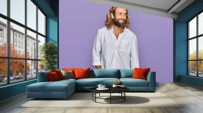 Handsome man with beard and long hair wearing casual clothes looking away to side with smile on face, natural expression. laughing confident. Wall mural