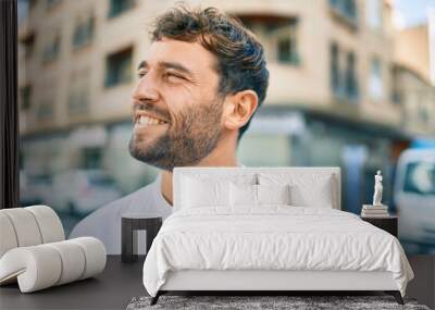 Handsome man with beard wearing casual white shirt on a sunny day smiling happy outdoors Wall mural