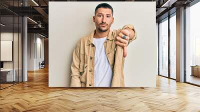 Handsome man with tattoos wearing casual brown denim jacket looking unhappy and angry showing rejection and negative with thumbs down gesture. bad expression. Wall mural