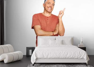 Handsome middle age man wearing casual clothes with a big smile on face, pointing with hand and finger to the side looking at the camera. Wall mural