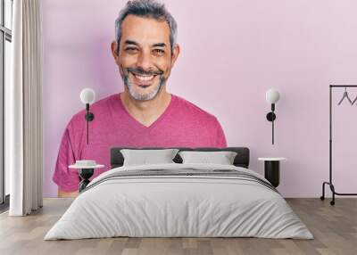 Handsome middle age man with grey hair wearing casual pink t shirt with a happy and cool smile on face. lucky person. Wall mural